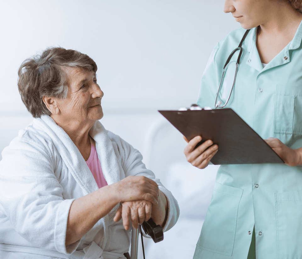 Young female physician talks to elderly patient with clipboard in her hand.