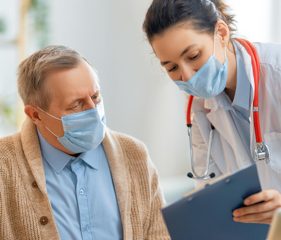 A doctor in a mask shares medical notes on clipboard with elderly male patient also wearing a mask.