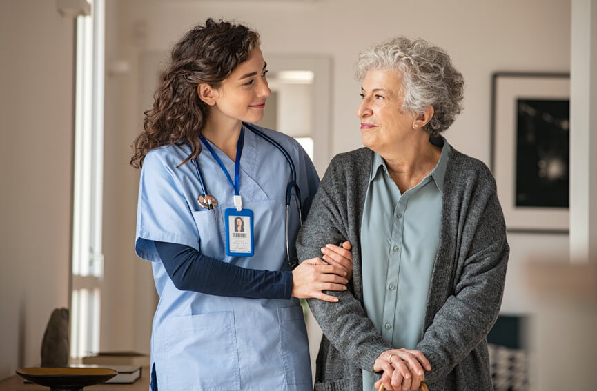 Female medical professional assists elderly female in her own home.