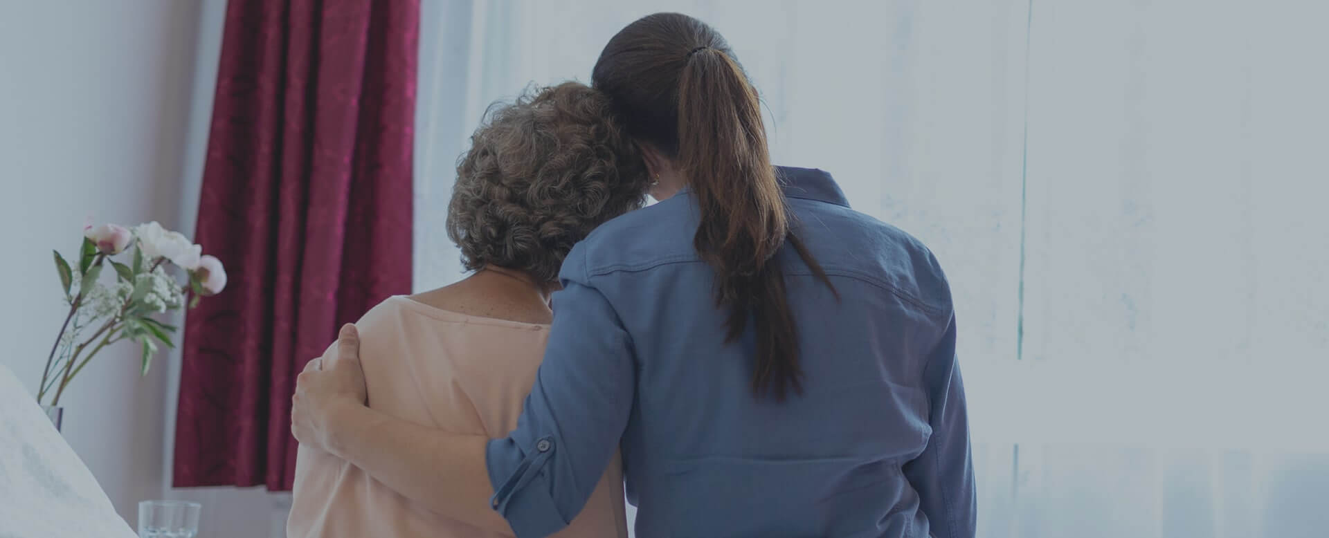 Caregiver embraces elderly client as she provides personal care services for her.